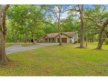 Charming single-Gathering home features a spacious front yard with mature trees and a two car garage at 19555 Phillips Rd, Brooksville, FL 34604