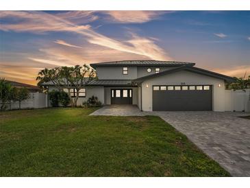 Stunning two-story home with a well-manicured lawn and a modern gray driveway leading to the two-car garage at 319 Midway Is, Clearwater Beach, FL 33767