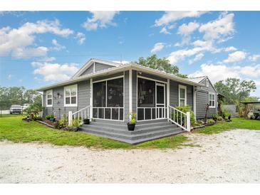 Charming home featuring a screened-in front porch, manicured landscaping, and a freshly painted exterior at 36725 Arcadia Ave, Myakka City, FL 34251