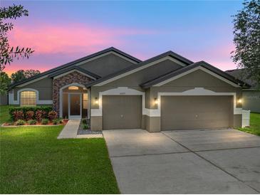Charming single-story home with a three car garage and well-manicured lawn and stone facade at 6957 Boulder Run Loop, Wesley Chapel, FL 33545