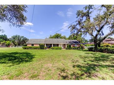 Charming ranch-style home with a well-manicured lawn and lush greenery on a sunny day at 9918 Davis Rd, Tampa, FL 33637