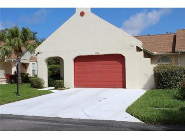 Attached garage with a red door and ample driveway space, perfect for parking and curb appeal at 11541 Orleans Ln, Port Richey, FL 34668