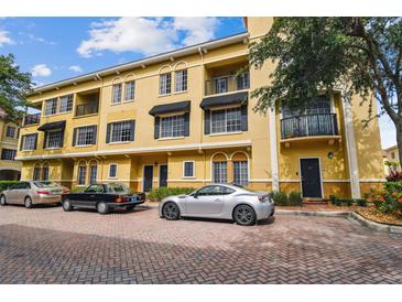 Three-story condo building with brick-paved parking area and multiple cars parked out front on a sunny day at 119 Beach Haven Ln, Tampa, FL 33609