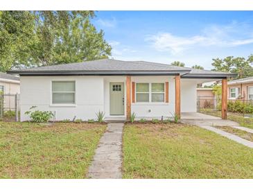 Charming single-story home with fresh white brick, natural wood posts, green door, and a well-manicured lawn at 1713 W Saint John St, Tampa, FL 33607
