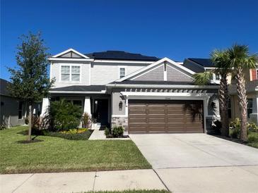 Two-story home boasts a well-manicured lawn, palm trees, a two-car garage and solar panels at 33560 Castaway Loop, Wesley Chapel, FL 33543