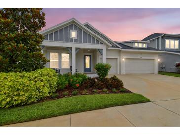 Charming single Gathering home with a three-car garage, inviting front porch, and beautiful landscaping at 7616 Paradiso Dr, Apollo Beach, FL 33572