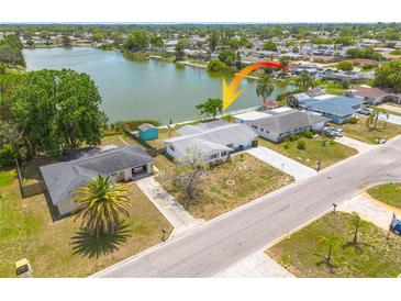 Aerial view of waterfront home with a large yard, mature trees and a beautiful lake view at 8014 Lotus Dr, Port Richey, FL 34668