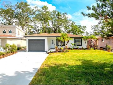 Charming single-story home with lush green lawn, a gray garage door, and well-manicured landscaping at 8335 42Nd N Ave, St Petersburg, FL 33709