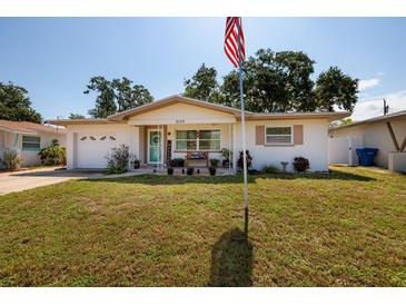 Charming single-story home with a well-maintained lawn, American flag, and inviting front porch at 2135 Pocahontas Dr, Largo, FL 33774