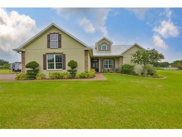 Inviting exterior of home featuring a lush lawn, mature landscaping, and charming architectural details at 3212 E Merrin Rd, Plant City, FL 33567