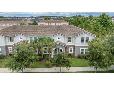 Inviting two-story home with a well-manicured lawn, stone accents, and a charming tiled roof at 13306 Wildgrass Trl, Odessa, FL 33556