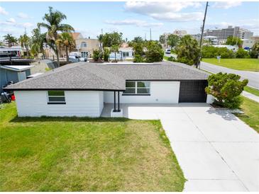 Inviting single-story home with a spacious front yard, a black garage door, and a concrete driveway at 13715 Maria Dr, Hudson, FL 34667