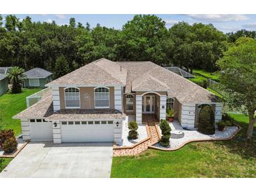 Charming two-story home featuring a manicured lawn, beautiful landscaping, and a two-car garage at 1460 Kensington Woods Dr, Lutz, FL 33549