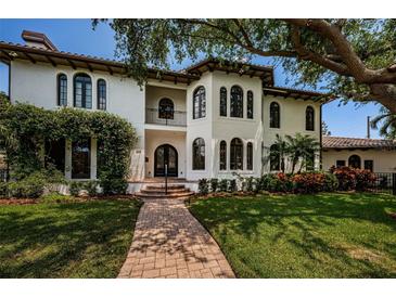Elegant stucco home features arched windows, a Juliet balcony, and lush landscaping at 147 Bay Point Ne Dr, St Petersburg, FL 33704