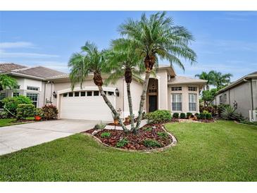 Charming home featuring a two-car garage, palm trees, and well manicured landscaping at 1528 Riverdale Dr, Oldsmar, FL 34677