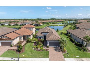 An aerial view of a single-Gathering home with a lush green lawn, terracotta roof, and serene lake backdrop at 3167 Forsythia Dr, Odessa, FL 33556