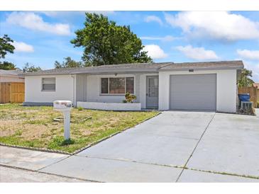 Charming single-story home with a well-maintained lawn and a one-car garage on a sunny day at 7330 Abalone Dr, Port Richey, FL 34668