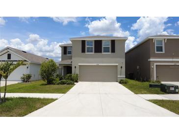 Charming two-story home with a well-manicured lawn and a spacious two-car garage at 16728 Kingman Reef St, Wimauma, FL 33598