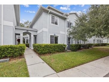 Charming exterior townhome with manicured green lawn, pathway and lovely neutral paint at 7410 E Bank Dr, Tampa, FL 33617