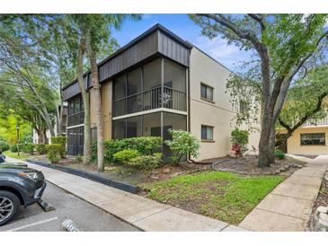 Inviting condo exterior featuring a screened balcony surrounded by lush landscaping and mature trees at 11805 Raintree Lake Ln # A, Tampa, FL 33617