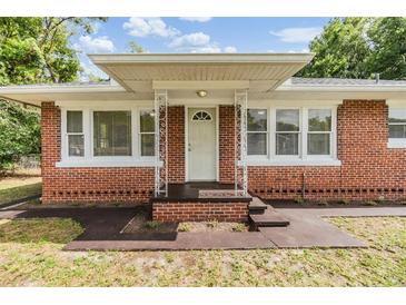 Charming brick home featuring a covered entry with decorative metal support columns and large windows at 1511 Emma E St, Tampa, FL 33610