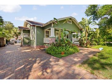 Charming green home with brick walkway, lush landscaping, and inviting curb appeal at 216 W South Ave, Tampa, FL 33603