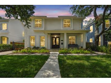 Charming two-story home featuring a manicured lawn, lush landscaping, and a welcoming front porch with a bench at 2522 W Watrous Ave, Tampa, FL 33629