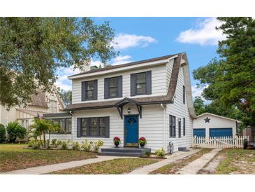 Charming two-story home boasts a blue door, gray shutters, and manicured landscaping at 310 N Lincoln Ave, Clearwater, FL 33755
