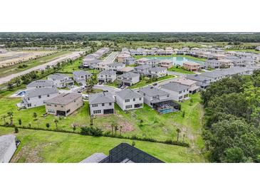 Aerial view of a neighborhood with well-maintained houses, green lawns, and community pond at 3541 Great Banyan Way, Wesley Chapel, FL 33543