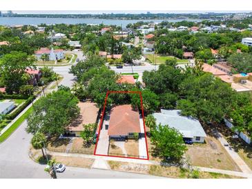 An aerial view of a charming single-story home featuring a classic red tile roof, surrounded by lush greenery in a vibrant neighborhood at 120 Bosphorous Ave, Tampa, FL 33606