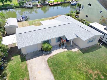 Aerial view of a charming single-story home with a well-maintained lawn, boat lift, and canal access at 13928 Raie Ave, Hudson, FL 34667