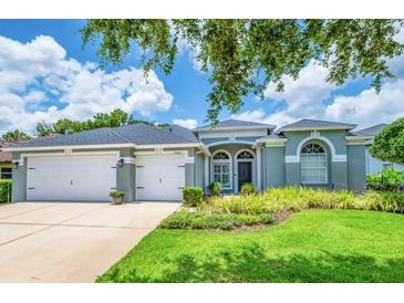 Charming single-story home boasts a two-car garage and a beautifully landscaped front yard with lush green grass at 15309 Palomapark Ln, Lithia, FL 33547
