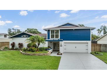 Charming two-story home with a vibrant blue accent and lush landscaping at 15609 Gardenside Ln, Tampa, FL 33624