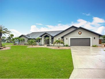 Charming single-story home features a well-manicured lawn, lush landscaping, and a neutral color palette at 27466 Tierra Del Fuego Cir, Punta Gorda, FL 33983