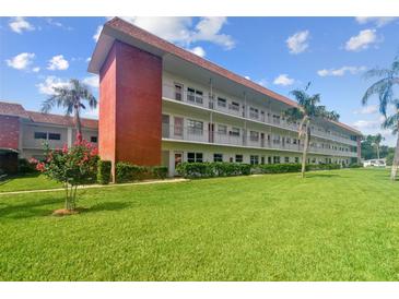 Three-story condo building with white facade, red accents, and landscaped green lawn and palm trees at 5728 14Th N Ave # 101B, St Petersburg, FL 33710