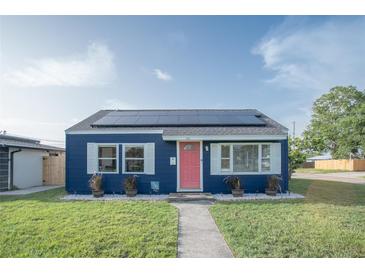 Charming blue home with solar panels, a pink door, and well-manicured lawn at 1001 57Th N Ave, St Petersburg, FL 33703