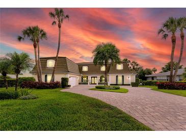 Stunning two-story home featuring lush landscaping, brick driveway, and elegant architectural details during a beautiful sunset at 224 Harbor View Ln, Largo, FL 33770