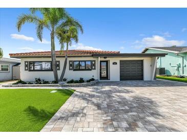 Charming single-story home with a well-manicured lawn, paver driveway, and beautiful landscaping at 241 176Th Terrace E Dr, Redington Shores, FL 33708