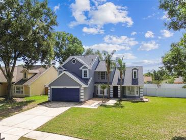 Charming two-story home with a well-manicured lawn, lush trees, and a two-car garage at 10208 Evening Trail Dr, Riverview, FL 33569