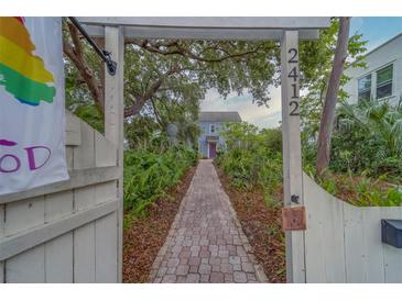 Inviting walkway leading to a charming home, framed by lush greenery and an arbor with visible address at 2412 Burlington N Ave, St Petersburg, FL 33713