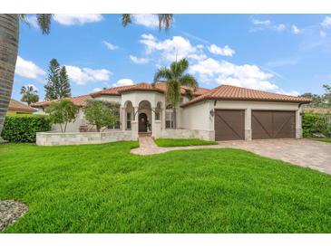 Elegant home featuring a lush green lawn and a clay tile roof with a two-car garage at 307 Palmetto Ln, Largo, FL 33770