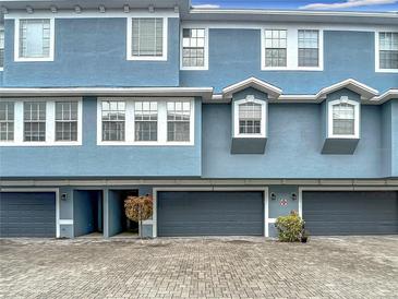 Charming townhome featuring a blue exterior, gray garage doors and beautiful brick driveway at 3111 W De Leon St # 2, Tampa, FL 33609