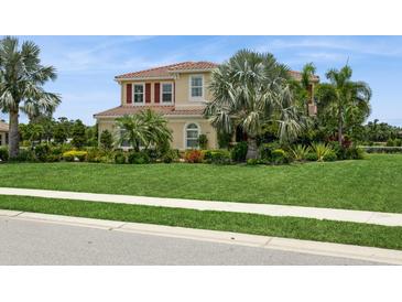 Stunning two-story home featuring lush landscaping, vibrant flowers, and a well-manicured lawn at 4973 Antiquity Way, Sarasota, FL 34240