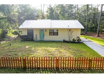 Charming single-story home with metal roof, tidy lawn, and a decorative picket fence at 10804 Bounty St, New Port Richey, FL 34654