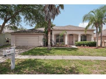 Charming single-story home features a well-maintained lawn, arched entryway, and attached two-car garage at 10905 Wildcat Dr, Riverview, FL 33579