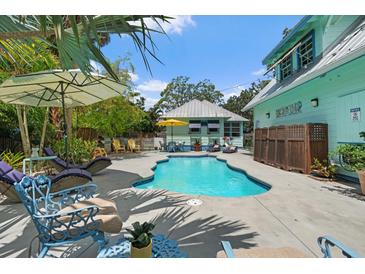 Backyard pool area framed by mature trees, comfortable lounge chairs, and shade umbrellas at 111 29Th W St, Bradenton, FL 34205