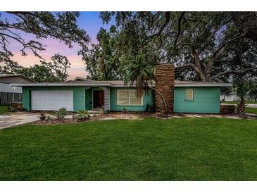 Charming single-story home with a well-manicured lawn, a stone chimney, and lush landscaping at 152 58Th S Ave, St Petersburg, FL 33705