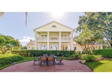 Beautiful outdoor patio featuring a large white home with a balcony and well manicured yard space at 15612 Howell Park Ln, Tampa, FL 33625