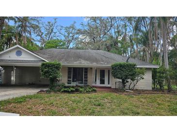 Charming single-story home featuring a lush front yard with mature trees and an attached carport at 17306 Livingston Ave, Lutz, FL 33559