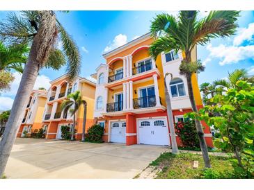 Colorful three-story townhomes with private garages and balconies, surrounded by lush palm trees and landscaping at 17817 Gulf Blvd # A, St Petersburg, FL 33708